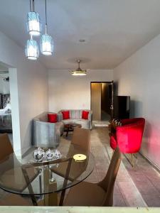 a living room with a glass table and red chairs at City suite sosua A in Sosúa