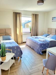 um quarto com 2 camas, uma mesa e uma janela em Willa Plażowa em Rewa