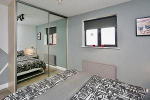1 dormitorio con cama y espejo en Neat City Apartment - Secure Parking - WiFi - Sleeps 4 - No Parties, en Belfast