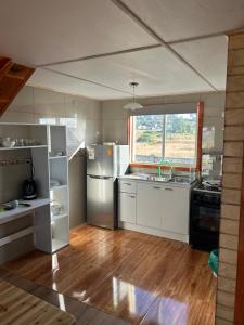 a kitchen with white appliances and a large window at Cabaña Loft del Sur Premium in Chonchi