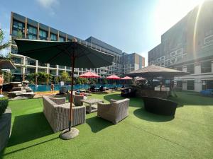 une terrasse avec des chaises et un parasol ainsi qu'une piscine dans l'établissement Laguna Beach Resort 2-have tub loft room, à Jomtien Beach