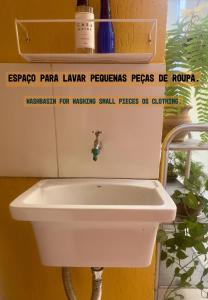 a white sink in a bathroom with a sign above it at CASA LUMEN Home Hostel in Núcleo Bandeirante