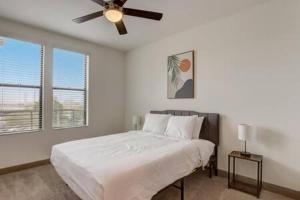 a white bedroom with a bed and a ceiling fan at Modern 2BR CozySuites on Town Lake waterfront 13 in Tempe