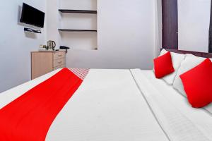 Schlafzimmer mit einem Bett mit roten und weißen Kissen in der Unterkunft Super OYO Flagship Royal Residency in Nāmakkal