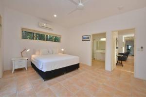 um quarto com uma cama branca e uma sala de estar em Villa Solina em Port Douglas
