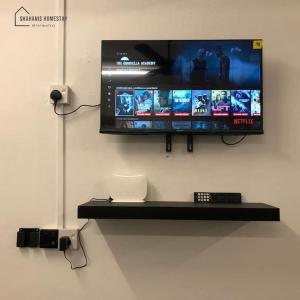 a flat screen tv hanging on a wall at Shahanis Homestay. A hotel-like stay experience! in Kijal