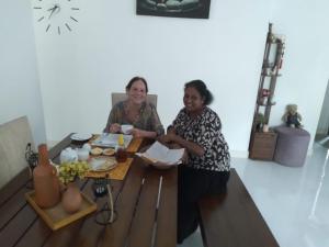 Deux femmes assises à une table dans une pièce dans l'établissement Elegant Hamlets Home Stay, à Chilaw