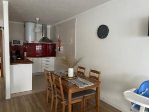 a kitchen with a table with chairs and a clock on the wall at Marquês de Pombal 55 in Peniche