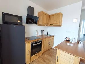 une cuisine avec un réfrigérateur noir et des armoires en bois dans l'établissement Appartement rénové au centre de Trébeurden, 400m de la plage, proche commerces - FR-1-368-407, à Trébeurden