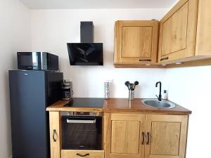 une petite cuisine avec un réfrigérateur et un évier dans l'établissement Appartement rénové au centre de Trébeurden, 400m de la plage, proche commerces - FR-1-368-407, à Trébeurden 7 autres photos