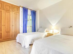 um quarto com 2 camas e uma janela com cortinas azuis em Apartamento L'Escala, 2 dormitorios, 6 personas - ES-89-130 em Torroella de Montgrí