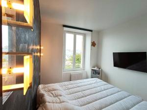 une chambre avec un lit et une télévision à écran plat dans l'établissement Appartement rénové au centre de Trébeurden, 400m de la plage, proche commerces - FR-1-368-407, à Trébeurden