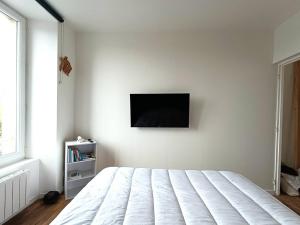 une chambre avec un lit et une télévision au mur dans l'établissement Appartement rénové au centre de Trébeurden, 400m de la plage, proche commerces - FR-1-368-407, à Trébeurden