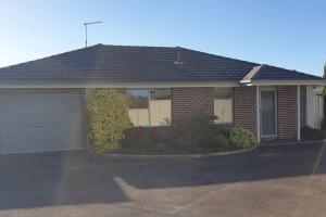 a red brick house with a garage at Shore beats working in Port Sorell