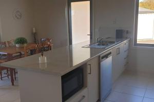 a kitchen with a counter top with a sink and a table at Shore beats working in Port Sorell