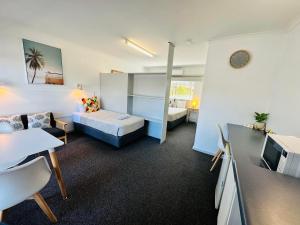 ビーチポートにあるBeachport Motor Innのベッド、ソファ、テーブルが備わる小さな客室です。