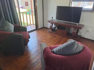 a living room with two couches and a flat screen tv at Berlydai Guest Accomodation in Secunda