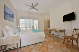 Schlafzimmer mit einem Bett, einem Schreibtisch und einem TV in der Unterkunft Solander House - 5 Bedrooms by the Beach in Port Douglas
