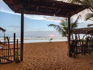 a beach with a hut and palm trees and the ocean at Ravana - Beach CABANAS in Hikkaduwa