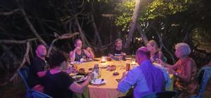 a group of people sitting around a table at night at Ravana - Beach CABANAS in Hikkaduwa