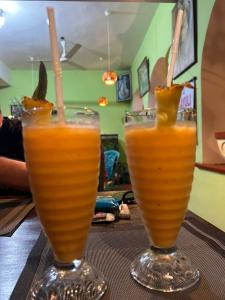 dos vasos de zumo de naranja sentados en una mesa en Ravana - Beach CABANAS, en Hikkaduwa