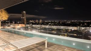 a rooftop pool with a view of the city at night at Amerittania 402 in Guadalajara