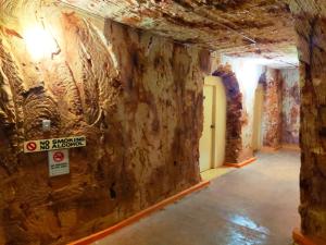 a room with a stone wall with a no entrance sign at Radeka Downunder Underground Motel in Coober Pedy