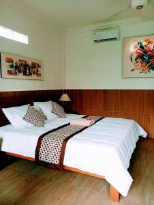 um quarto com uma cama grande com lençóis brancos e almofadas em Umah Dauh Homestay em Ubud