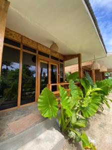 a house with large glass windows and plants in front at Dee Siargaonon Homestay in General Luna