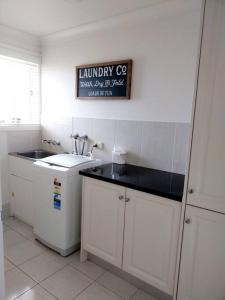 eine weiße Küche mit einem Waschbecken und einem Schild an der Wand in der Unterkunft Sunrise Retreat in Tamworth