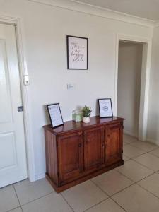 a wooden cabinet in a room with two pictures on it at Sunrise Retreat in Tamworth
