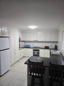 uma cozinha com armários brancos e um balcão preto em Sunrise Retreat em Tamworth