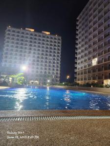 a large swimming pool in front of two buildings at night at Condo Mactan in Lapu Lapu City