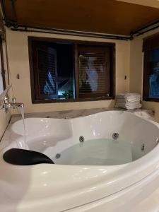 a white bath tub in a bathroom with two windows at Attanaya Malioboro Suites Yogyakarta in Sentool