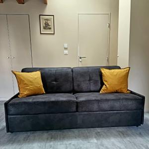 eine schwarze Couch mit zwei gelben Kissen drauf in der Unterkunft Henner des trois frontières in Saint-Louis