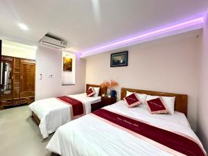 duas camas num quarto de hotel com luzes roxas em Ngọc Phương Anh Homestay Huế em Hue