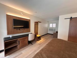 a large room with a bed and a flat screen tv at Bevonshire Lodge Motel in Los Angeles