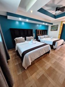 two beds in a room with blue walls at Hotel San Rafael in Poza Rica de Hidalgo