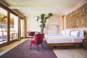 - une chambre avec un lit blanc et une chaise rouge dans l'établissement Kula Maya Boutique Hotel and Spa, à San Marcos La Laguna
