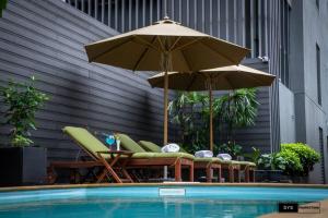 仰光Sayarsan Hotel Yangon的泳池旁边的一组椅子和遮阳伞