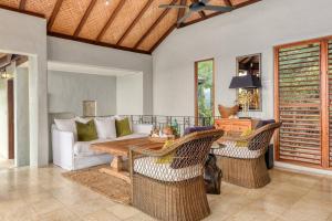 uma sala de estar com um sofá, uma mesa e cadeiras em Far Pavilion A - Stylish Villa with Tropical Views em Port Douglas