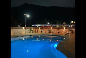 - une grande piscine avec des lumières bleues la nuit dans l'établissement Shalom Farmhouse Imphal, à Imphal