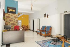 sala de estar con 2 sillas y TV en ORANGE VALLEY TOWN RESIDENCY, en Trivandrum