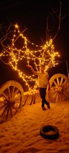 una persona in piedi sulla sabbia con delle luci di Sea pearl Homestay Kasarkod Honnavara a Kāsarkod