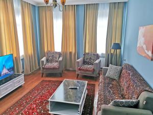 a living room with a couch and chairs and a tv at Bereket villa and aparts in Gabala