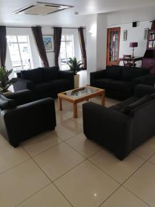 a living room with black couches and a coffee table at Airport Inn and Suites in Johannesburg