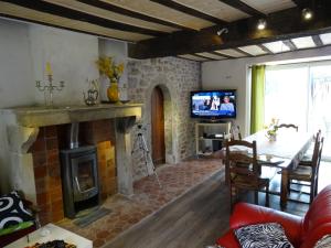 a living room with a fireplace and a table and a television at Datcha Bourguignonne, Chambres & Gîte in Maconge