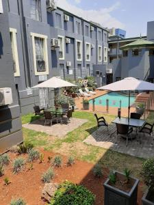 an outdoor patio with tables and umbrellas in front of a building at Airport Inn and Suites in Johannesburg