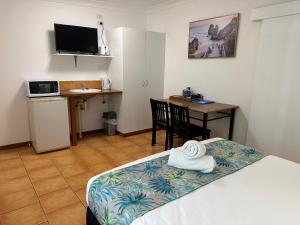 a room with a bed and a table and a desk at Cardwell Beachfront Motel in Cardwell