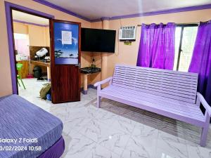 um quarto com um banco roxo e uma televisão em Einel Homestay 1 em Siquijor